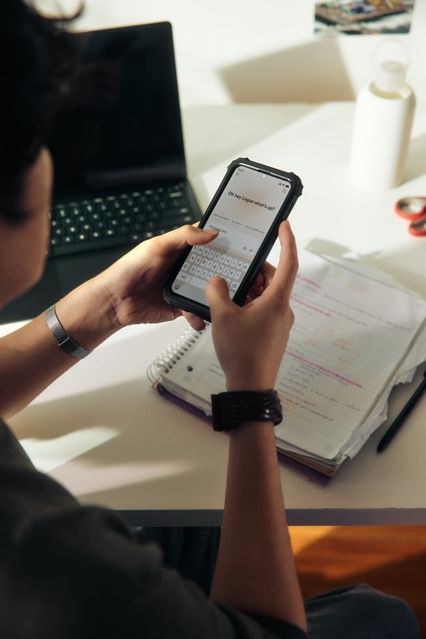 Personne prenant des notes, téléphone en main, à son bureau